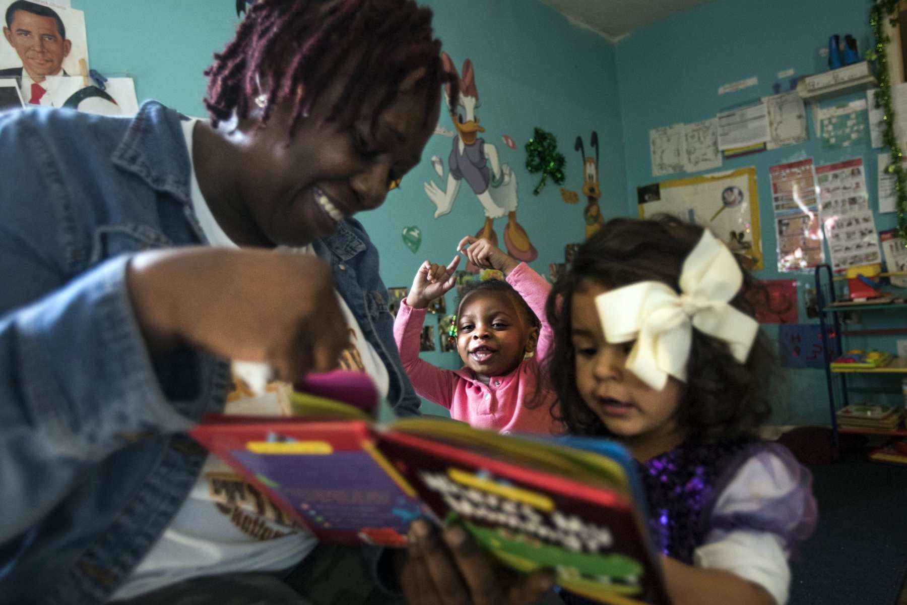 A woman reads a book to two small children.