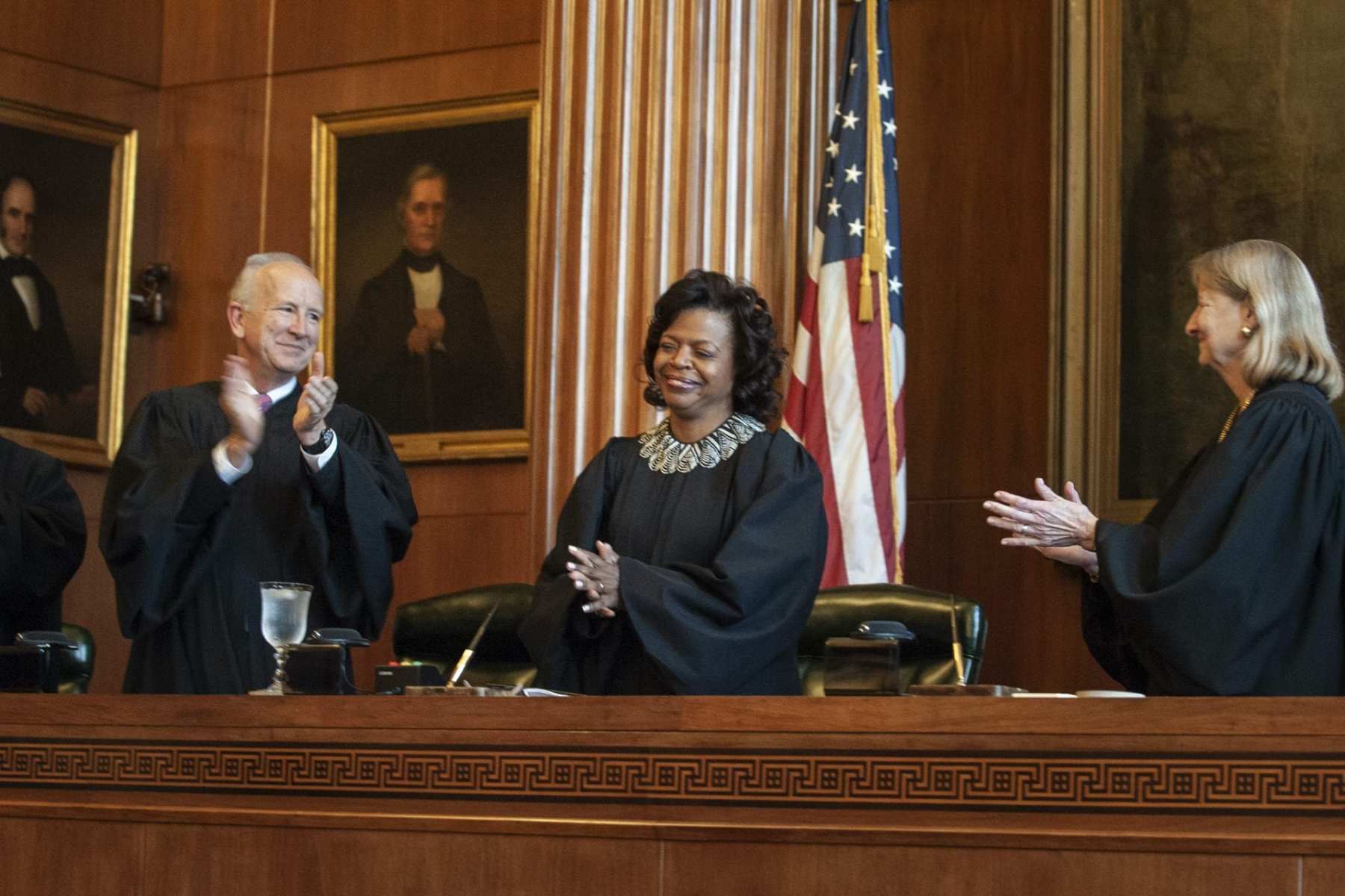 In this March 7, 2019 file photo, Associate Justices Paul Newby and Robin Hudson applaud for new Chief Justice Cheri Beasley, center, of the N.C. Supreme Court during Beasley's investiture ceremony in Raleigh. In North Carolina's Supreme Court chamber, above the seat held by Beasley, the second African American chief justice, hangs a towering painting of Chief Justice Thomas Ruffin, a 19th century slave owner and jurist who authored a notorious opinion about the “absolute” rights of slaveholders over the enslaved. In October 2018 the state Supreme Court named a commission to review the portraits in the building that houses the court ,including Ruffin's.  (Paul Woolverton/The Fayetteville Observer via AP)