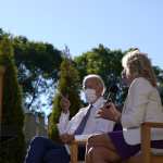 Joe and Jill Biden sit on a stage with masks on.