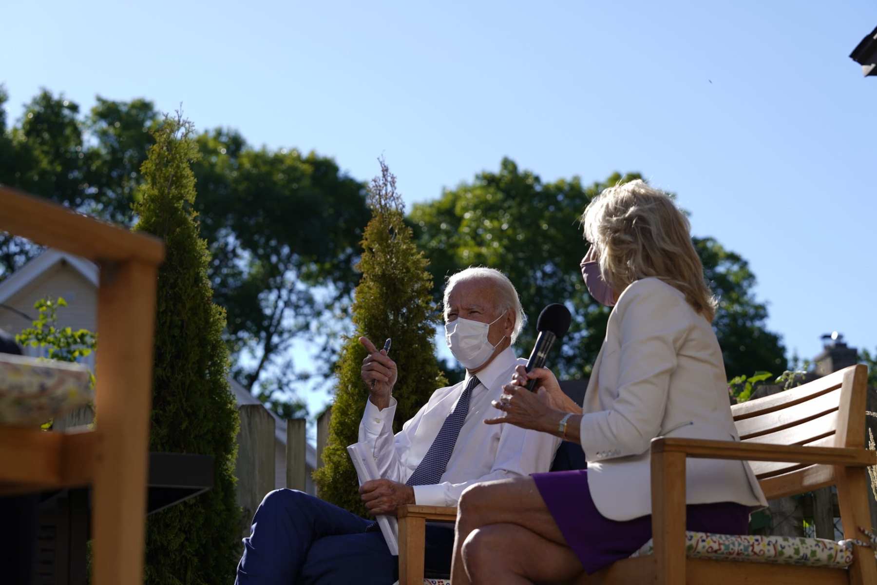 Joe and Jill Biden sit on a stage with masks on.