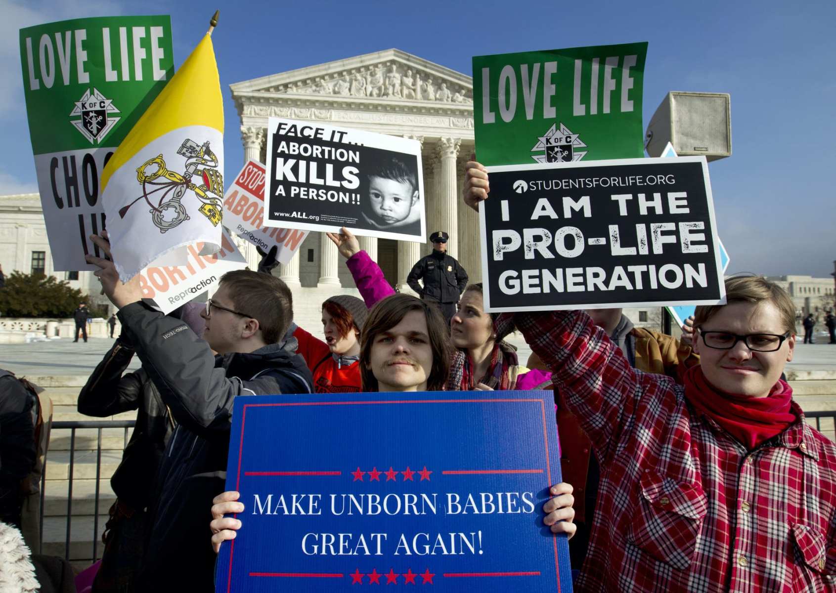 A group of protesters standing outside of the Supreme Court holding anti-abortion signs.