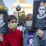 Two people carrying signs with Ruth Bader Ginsburg's face on them.