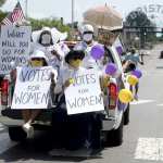 Women in all white sitting in the back of a truck with 