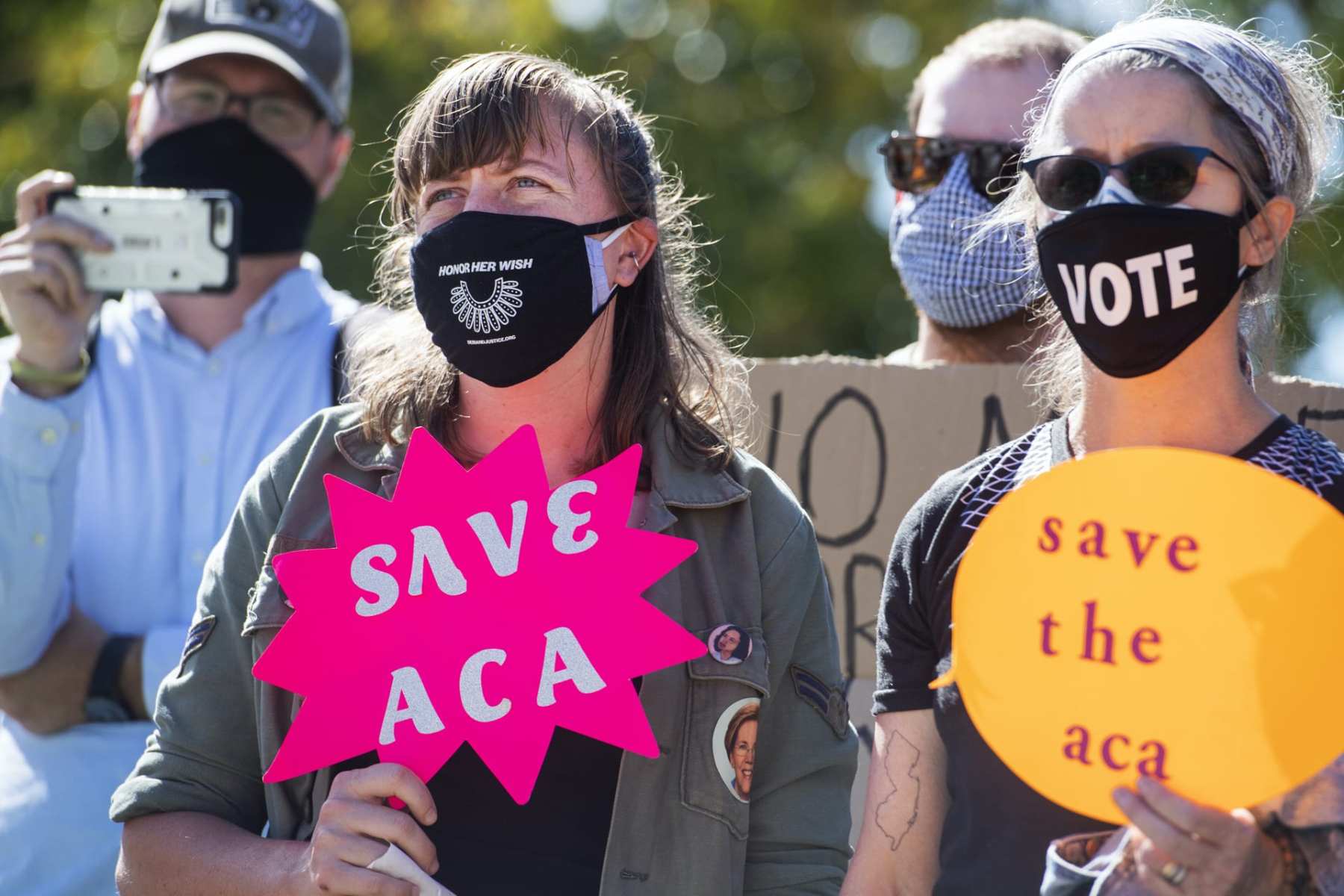 Protesters hold signs about the Affordable Care Act.