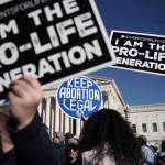 Protesters carry anti-abortion signs and abortion access signs.