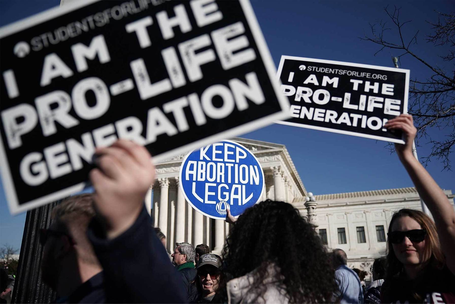 Protesters carry anti-abortion signs and abortion access signs.