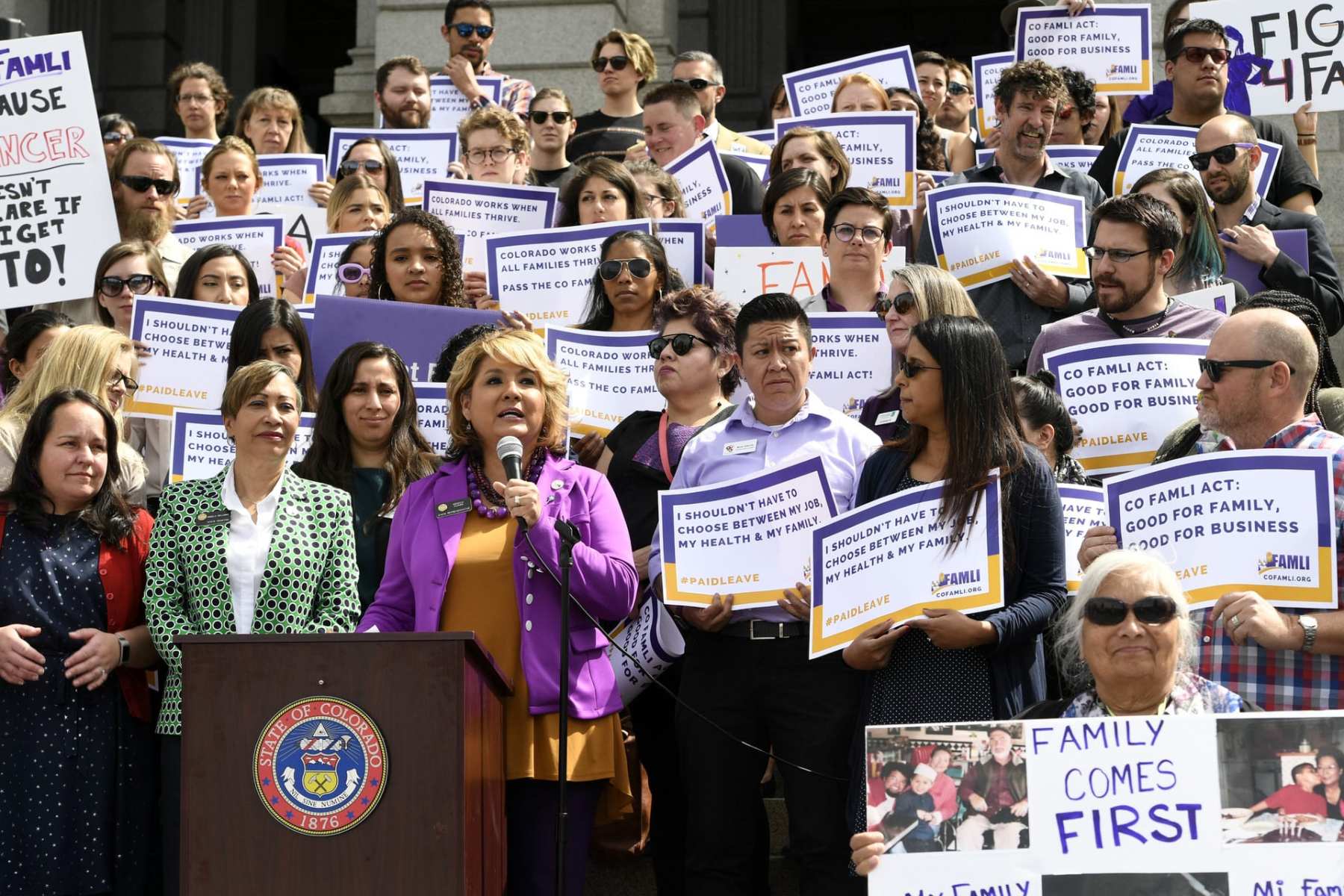 Protesters gather at a rally in Denver for paid family leave.