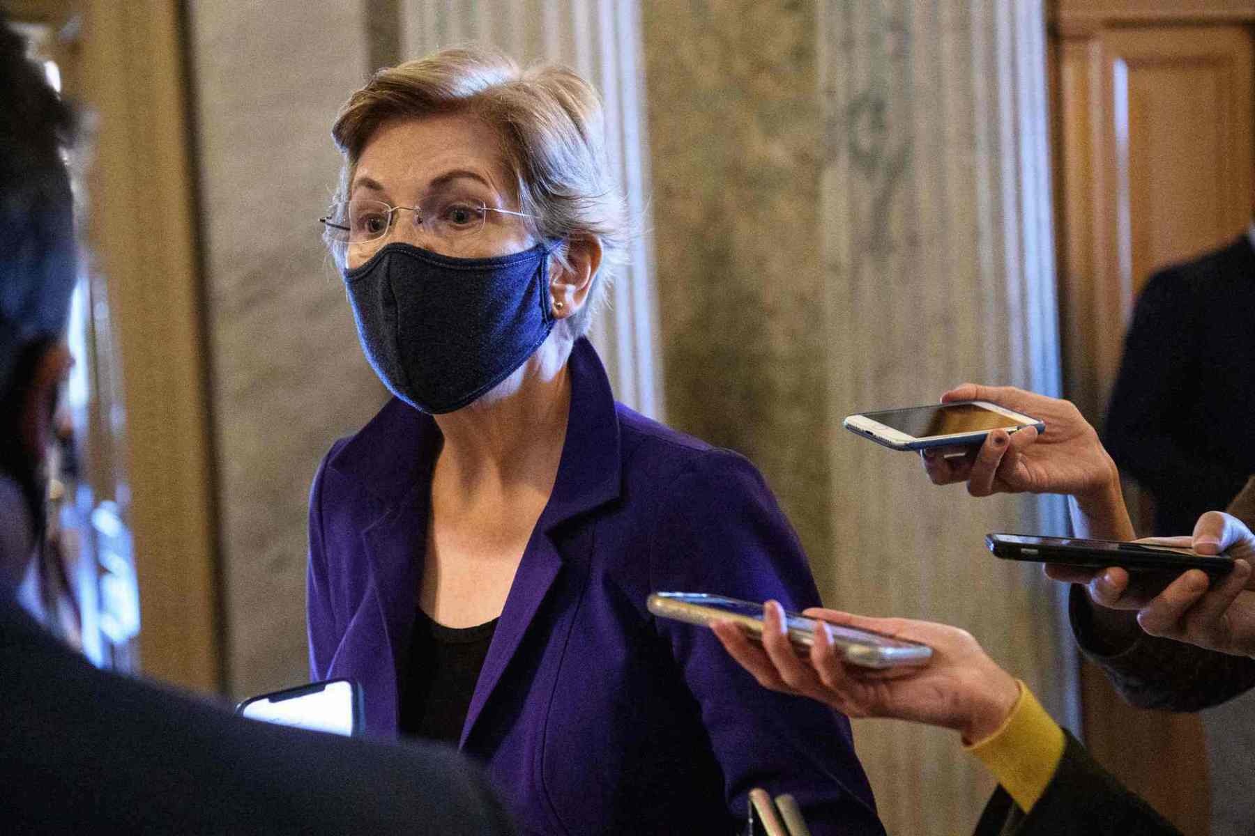 Sen. Elizabeth Warren surrounded by reporters holding phones to record.