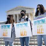 A group of people stand with signs that read 