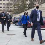 Dana Nessel walks escorted by three men.