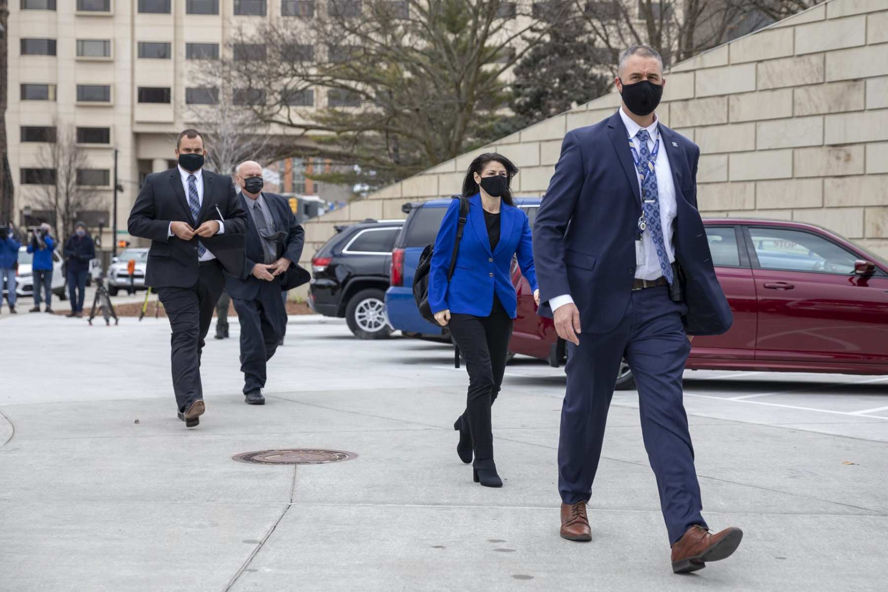 Dana Nessel walks escorted by three men.