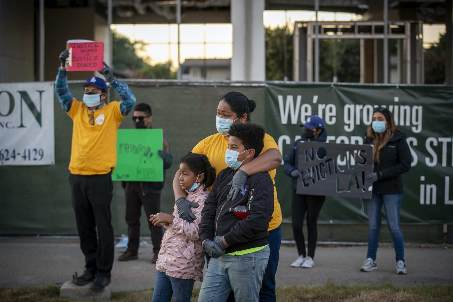 A woman stands with her two kids at a protest.