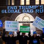 Activists from the Population Connection Action Fund hold signs in front of the Trump International Hotel..