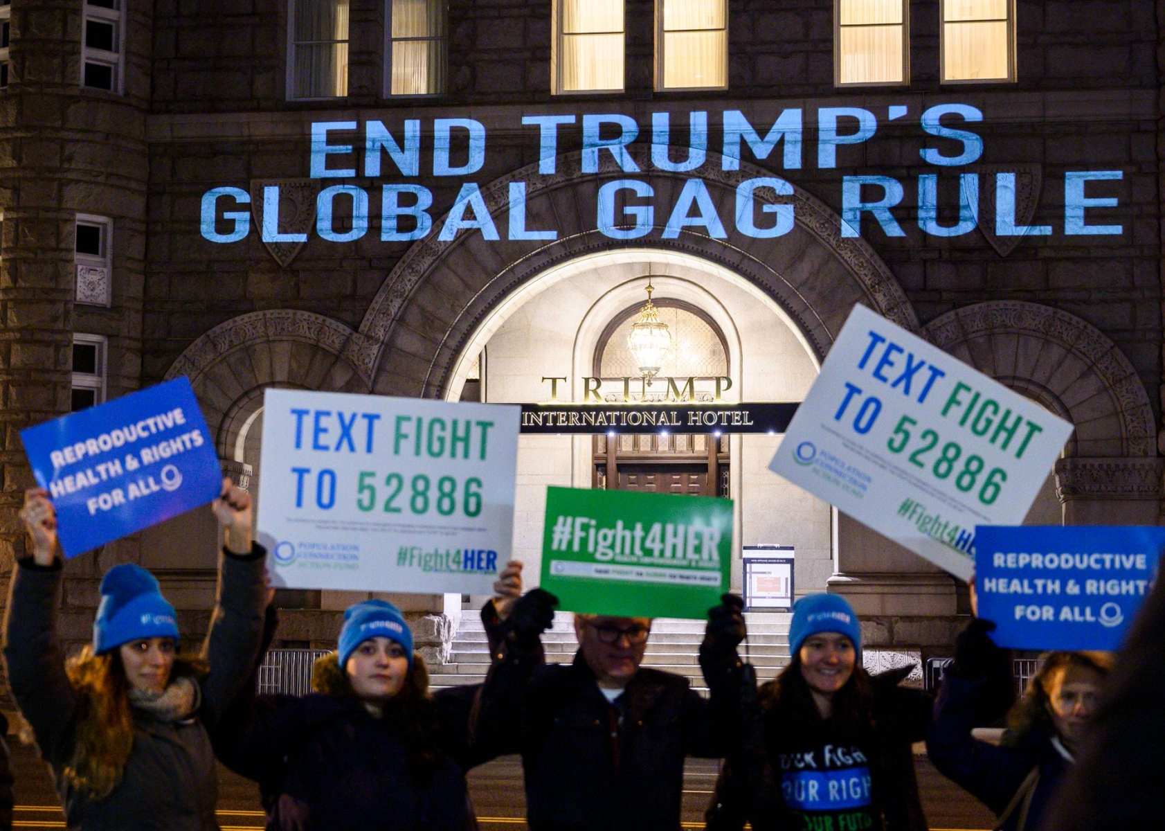 Activists from the Population Connection Action Fund hold signs in front of the Trump International Hotel..