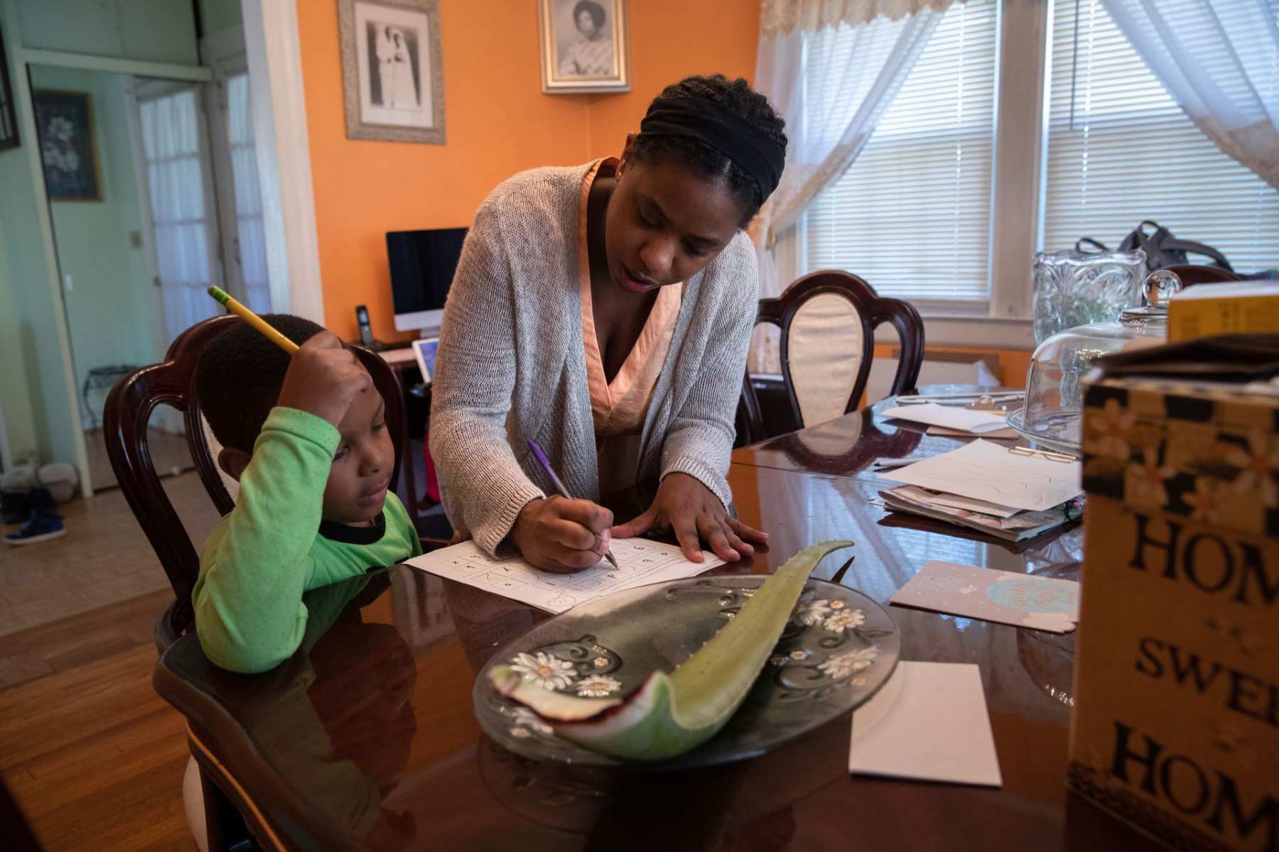 A mother helps her son with his school work at home.