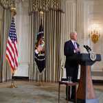 US Vice President Kamala Harris listens as US President Joe Biden speaks on racial equity at a podium in the White House state dining room.