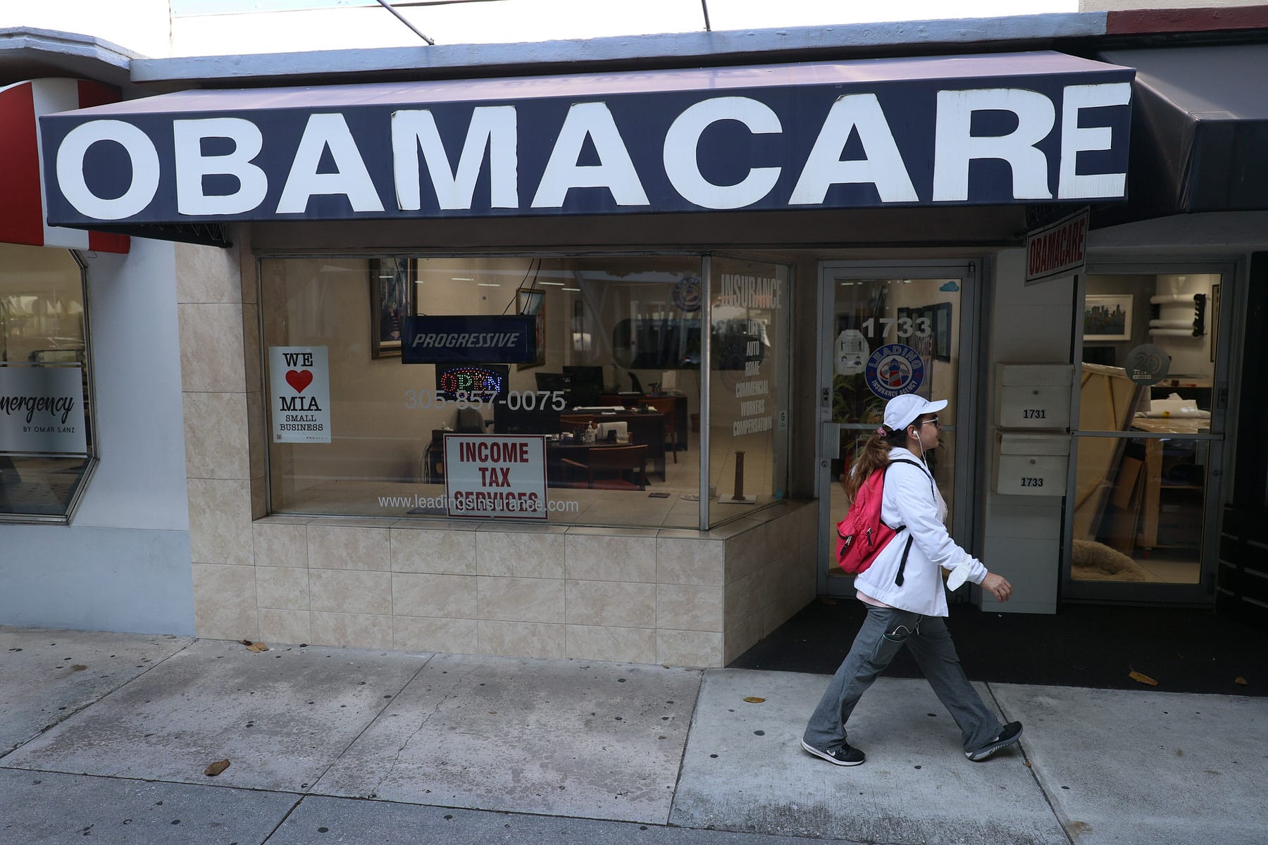 A woman walks past a lending agency with a large Obamacare sign.