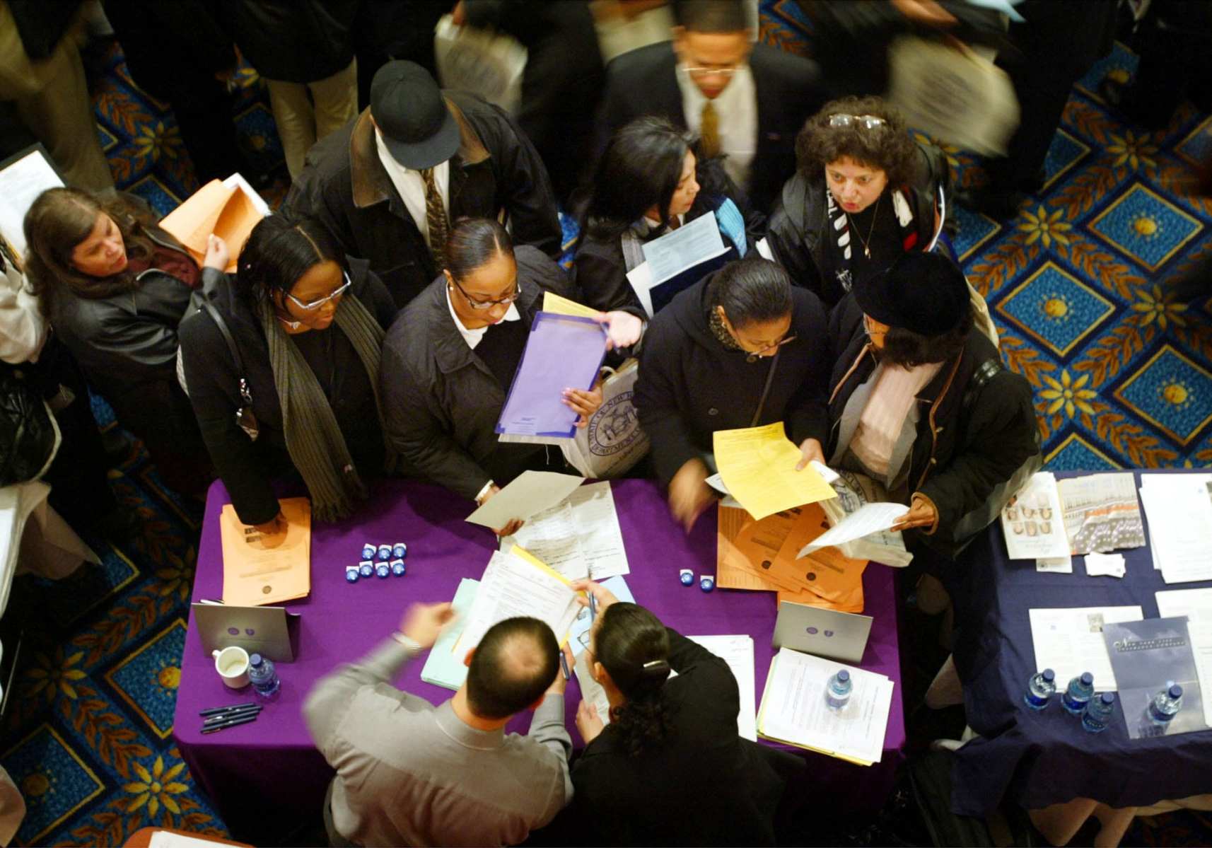 Job applicants gather around an employers table at Hispanic job fair.