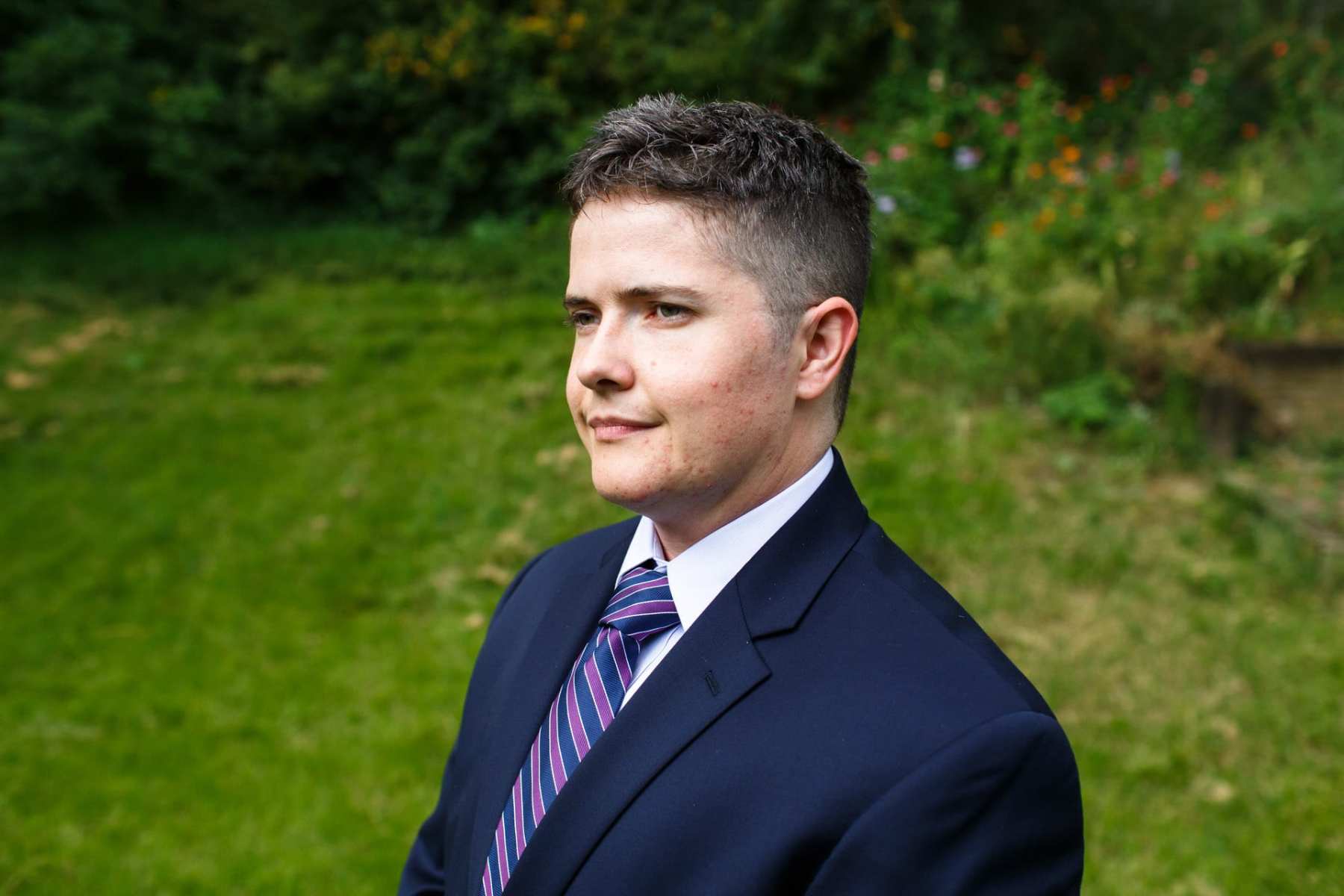 A man in a suit stands in a field.