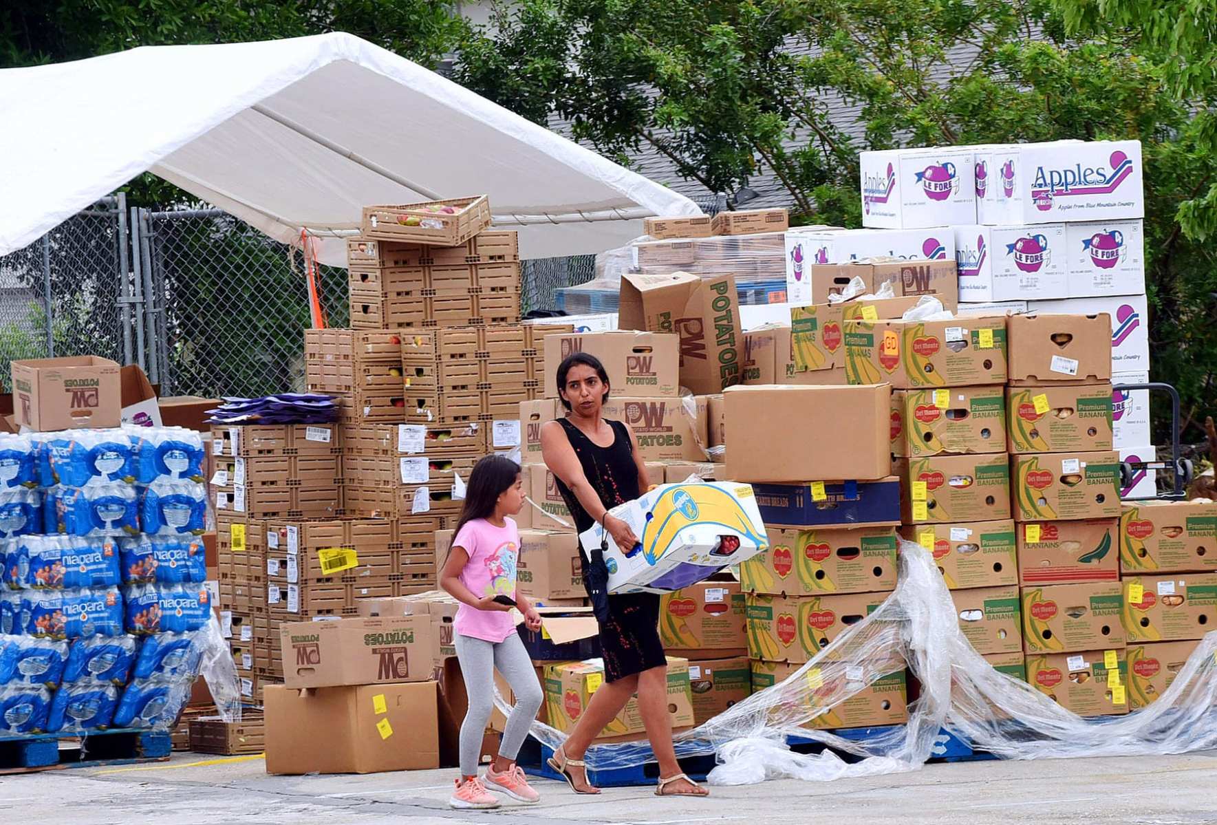 A woman with a child carries a box of food.