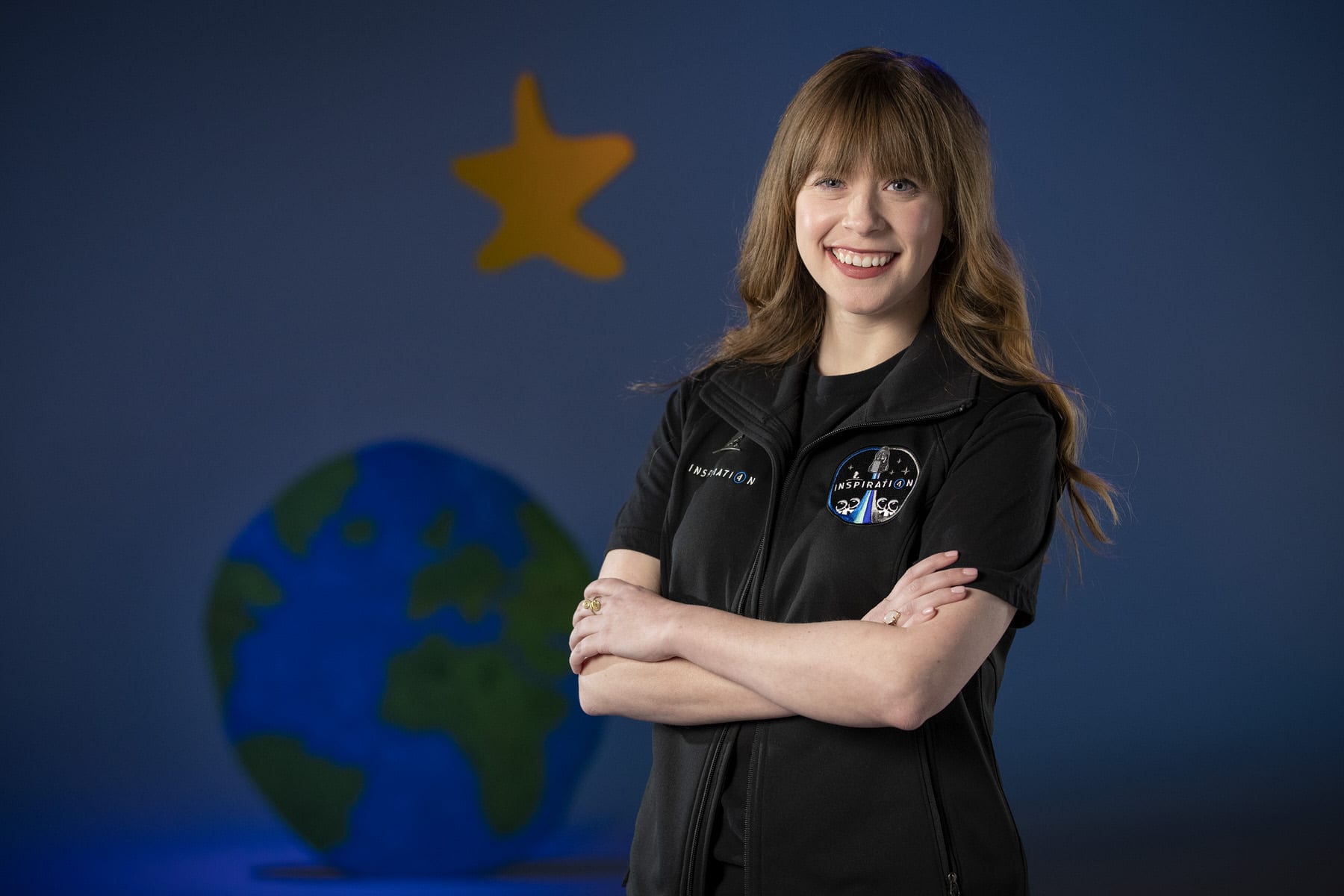 An image of Hayley Arceneaux standing in front of a mural.