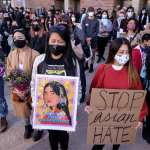 Demonstrators wearing face masks and holding signs take part in a rally