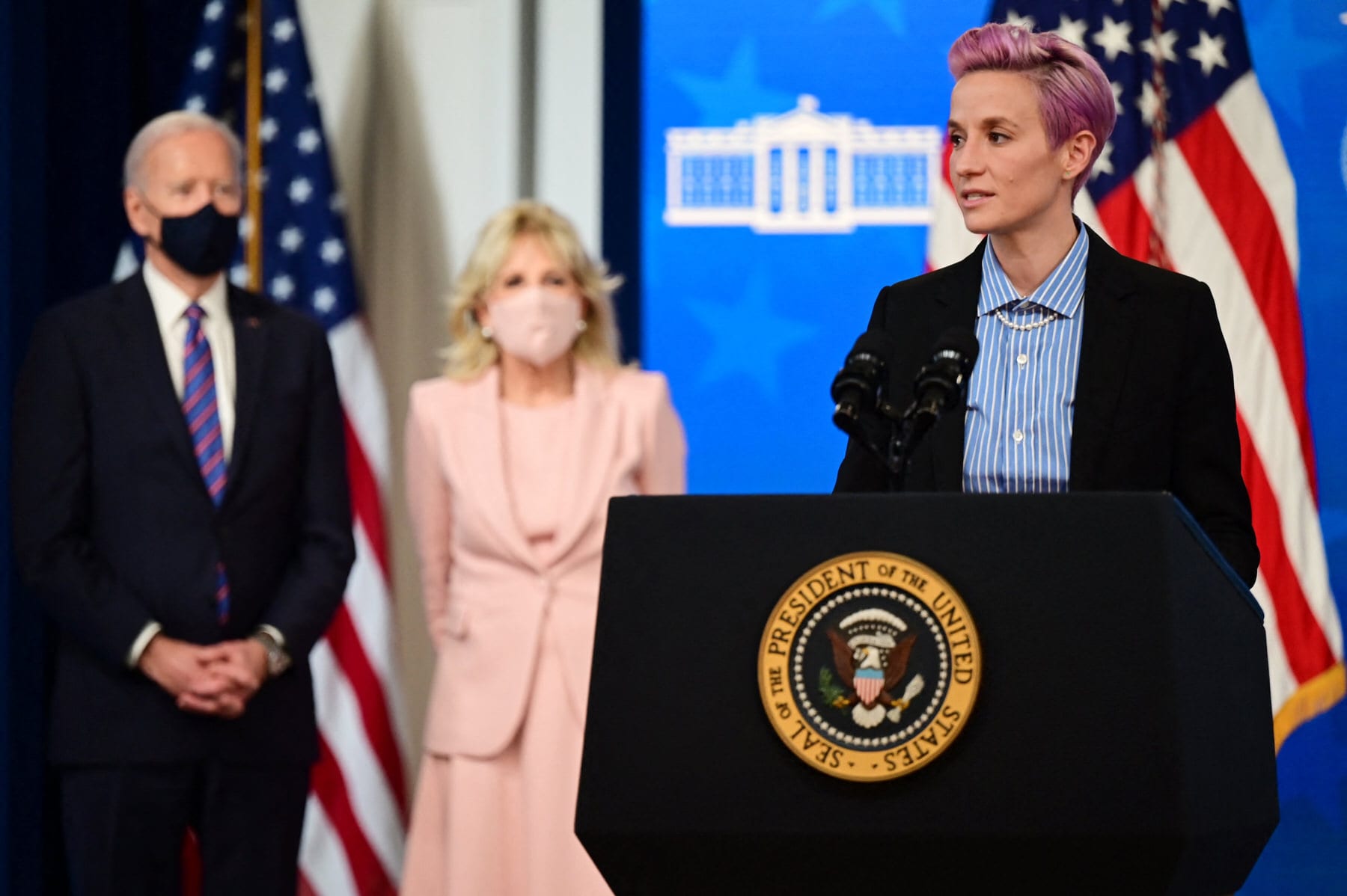 US soccer player Megan Rapinoe (R) speaks, flanked by US President Joe Biden (L) and First Lady Jill Biden during an Equal Pay Day event.