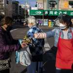 A grocery worker, right, passes a bundle of fresh longan to a woman.