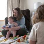 A mother reads to her children in a room.