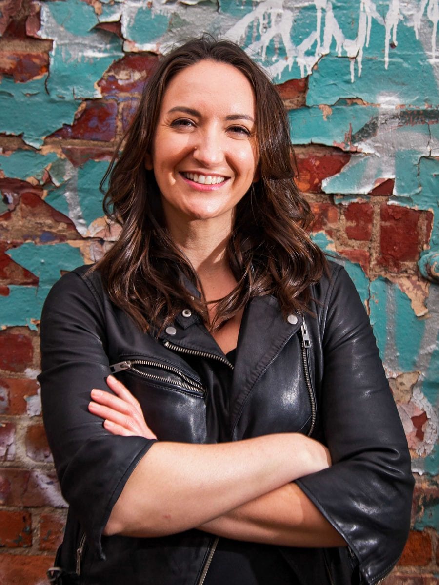 A photo of Sara Lind in front of a brick wall.