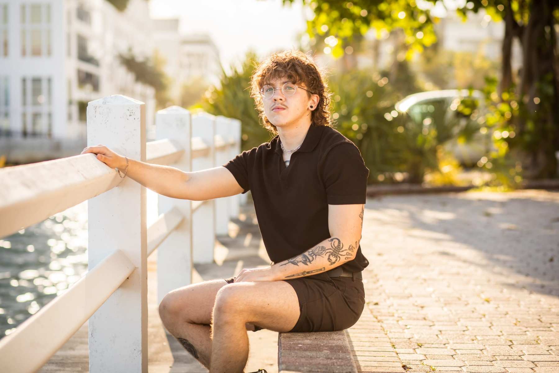 A man posing with his hand on a fence post.