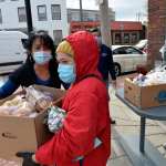 Gladys Vega, (left) Executive Director of the Chelsea Collaborative Inc. helps directing people in line in an effort to distribute food and packages of donated goods to people in need.