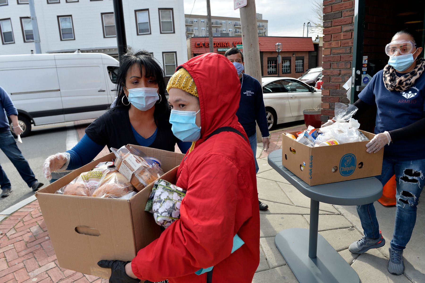 Gladys Vega, (left) Executive Director of the Chelsea Collaborative Inc. helps directing people in line in an effort to distribute food and packages of donated goods to people in need.