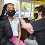 A young woman receives the Johnson & Johnson vaccine from.a pediatric nurse practitioner.