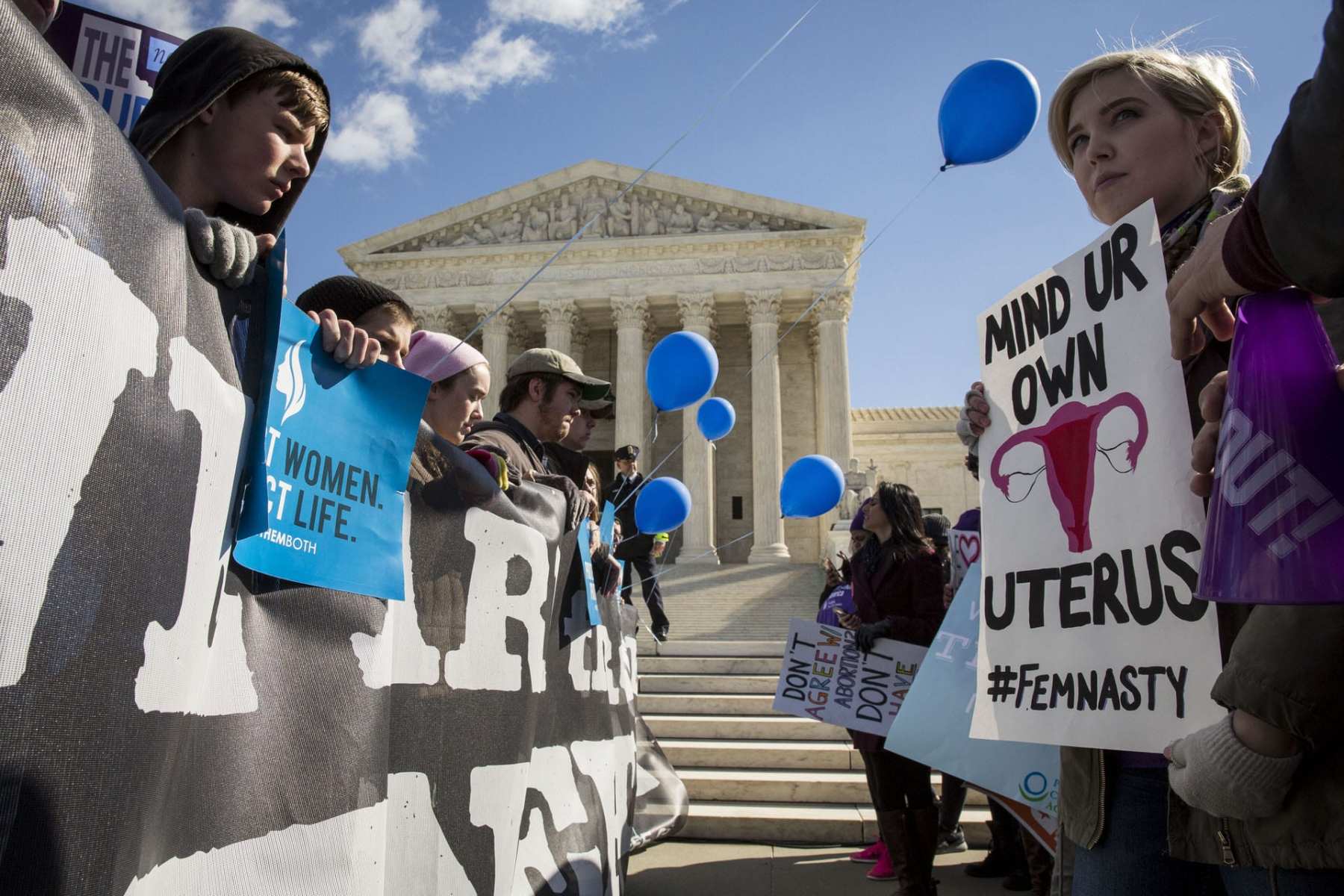 Protesters with both anti-abortion and abortion rights signs stand in front of the Supreme Court.