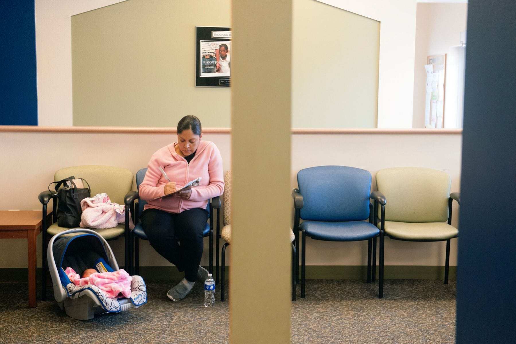 A woman fills out paperwork prior to a checkup with her 5-day old daughter.