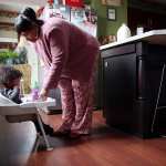 A woman leaning over a child in a high chair.