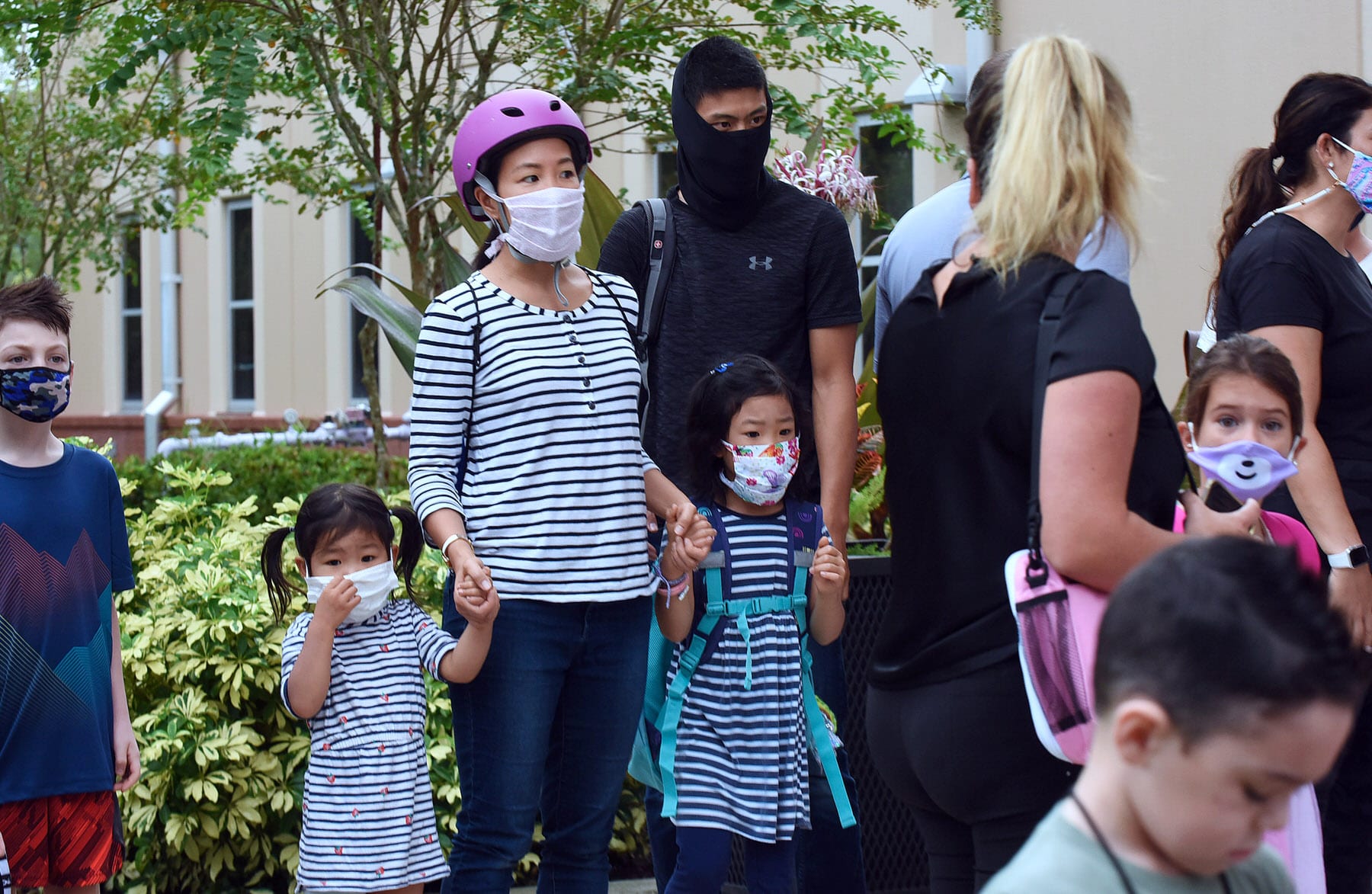 Children and their parents wait to enter the school building on the first day of in-person classes.