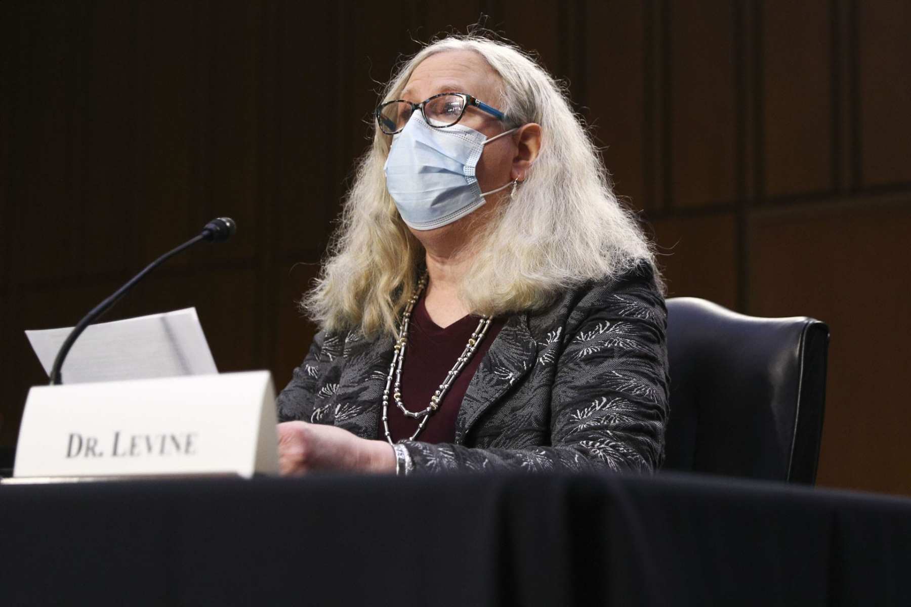 Dr. Rachel Levine speaking at a desk with a mask on.