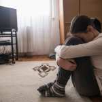 Teen woman with headache holding her head in her living room during the day