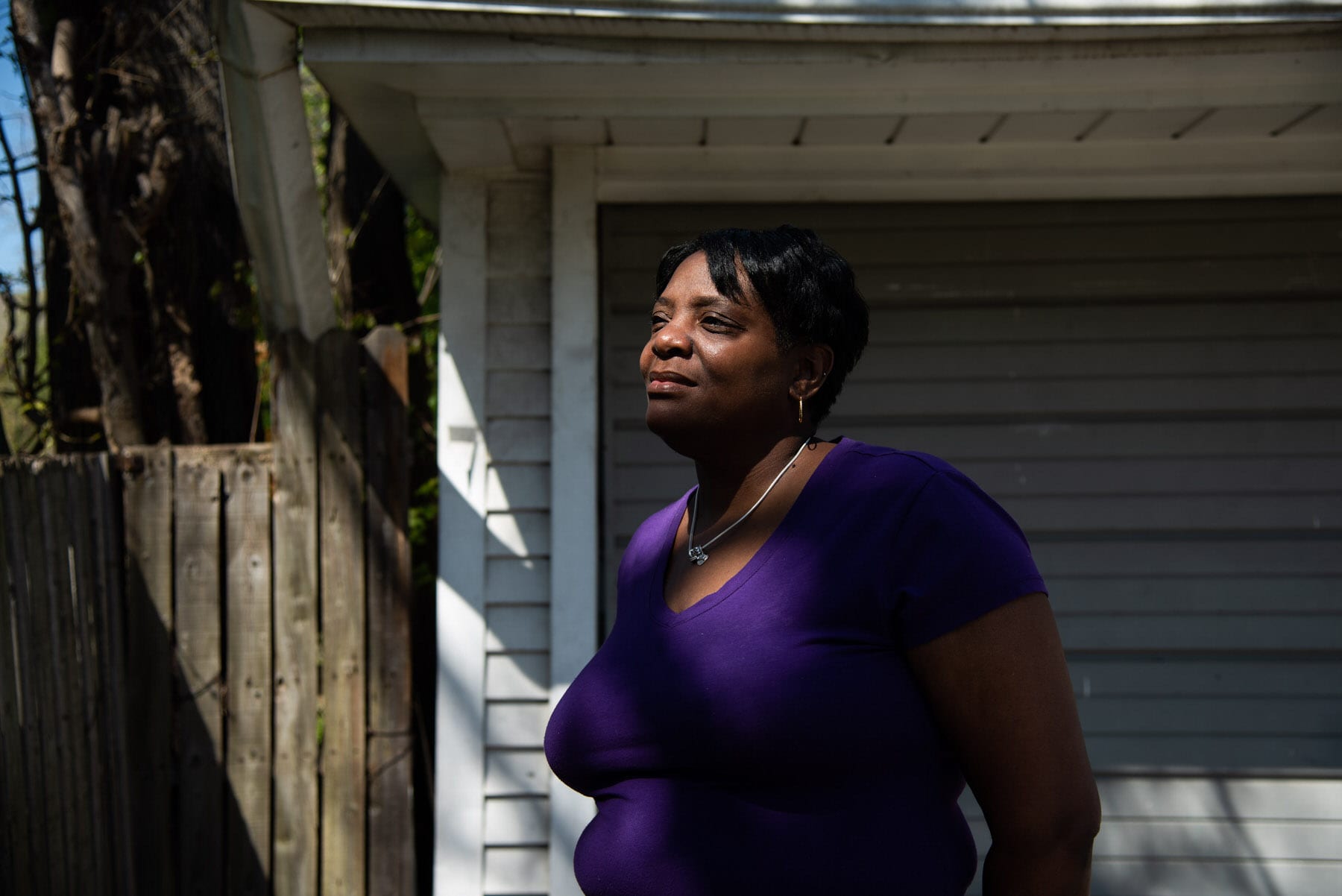 A woman stands in front of her garage.