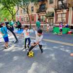 Kids playing soccer on a city street.