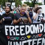 A group women hold a Juneteenth banner during a march.