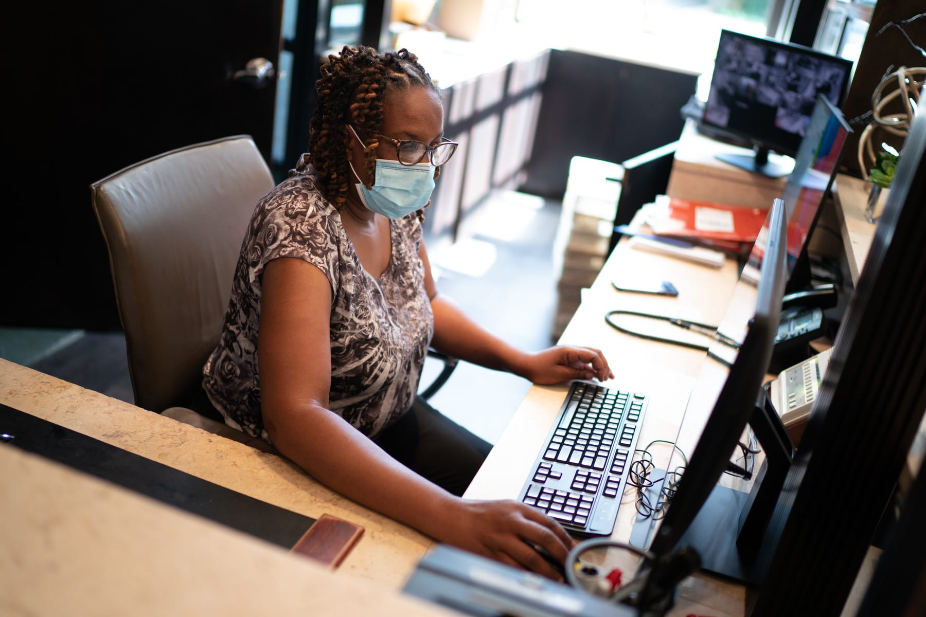 A Black women works behind a desk at an apartment building.