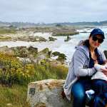 A mother breastfeeds her child by the water.