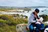 A mother breastfeeds her child by the water.