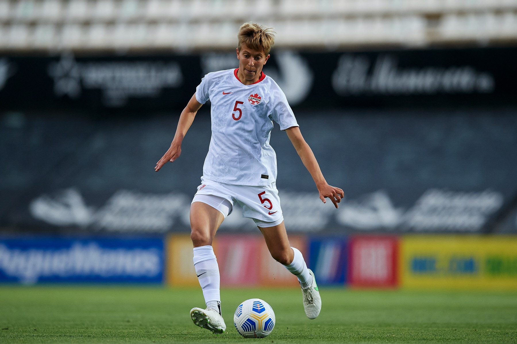 Soccer player Quinn about to kick a ball.