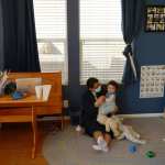 A woman sits on the floor with an infant.