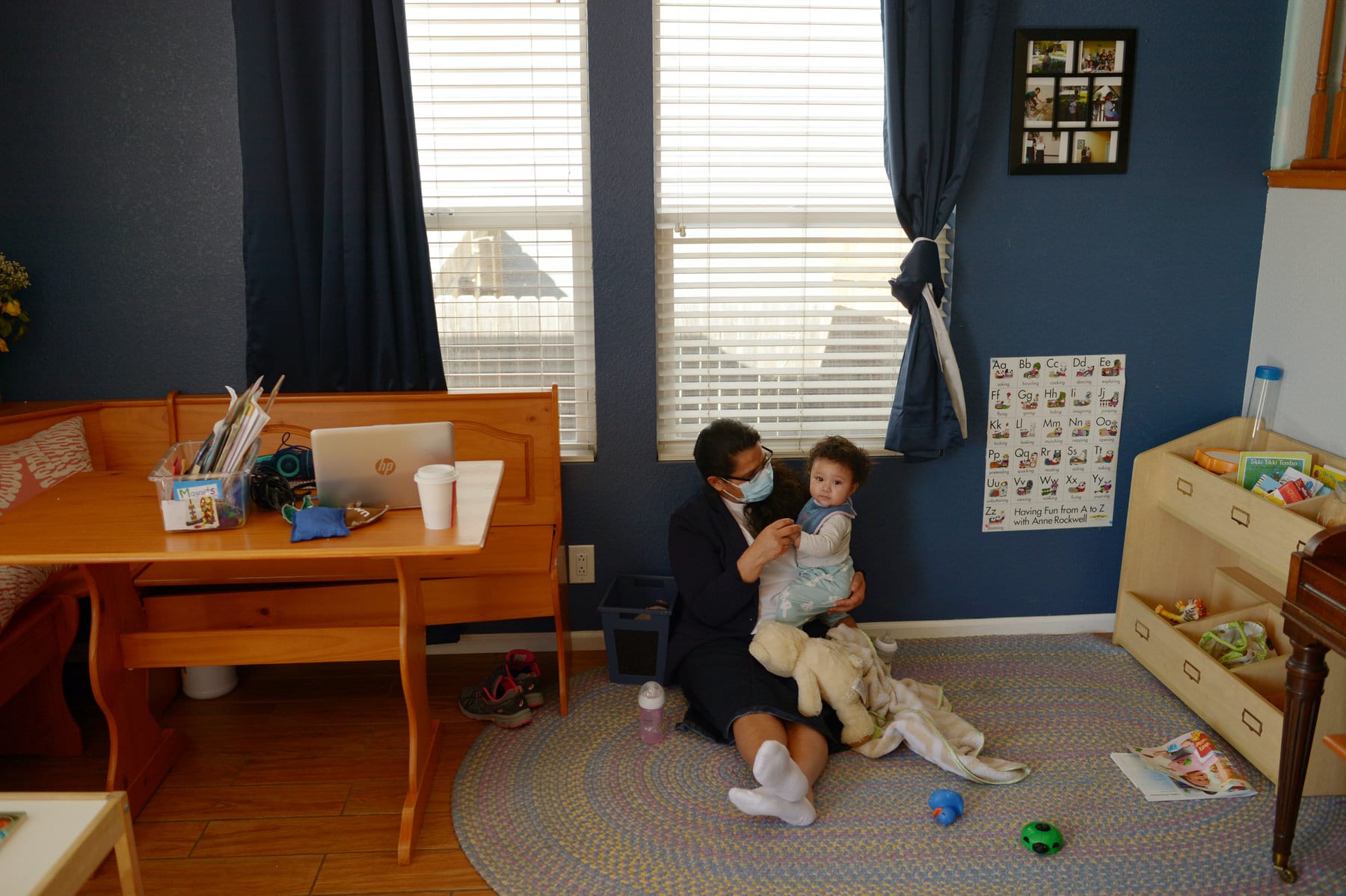 A woman sits on the floor with an infant.