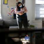 Diana Rastegayeva, who is on maternity leave with her children, with her 3-month-old in their home's living room in Somerville, MA on Feb. 26, 2021. Diana has created a website and recruited hundreds of volunteers who help people get vaccine appointments.